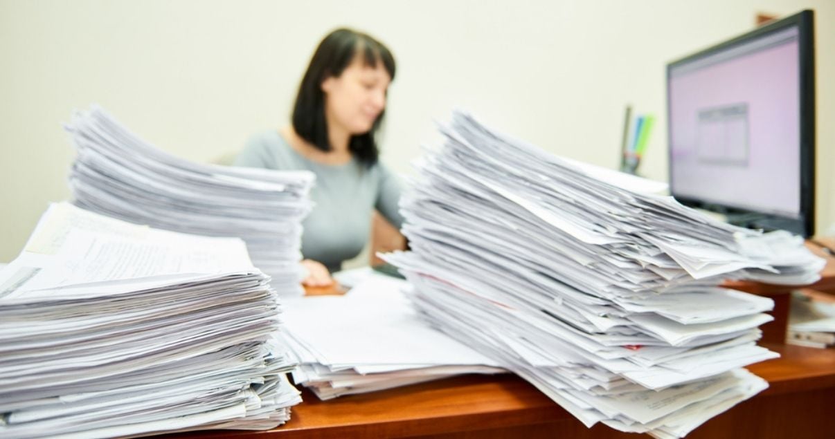 Businesswoman in front of her desk covered with paper forms
