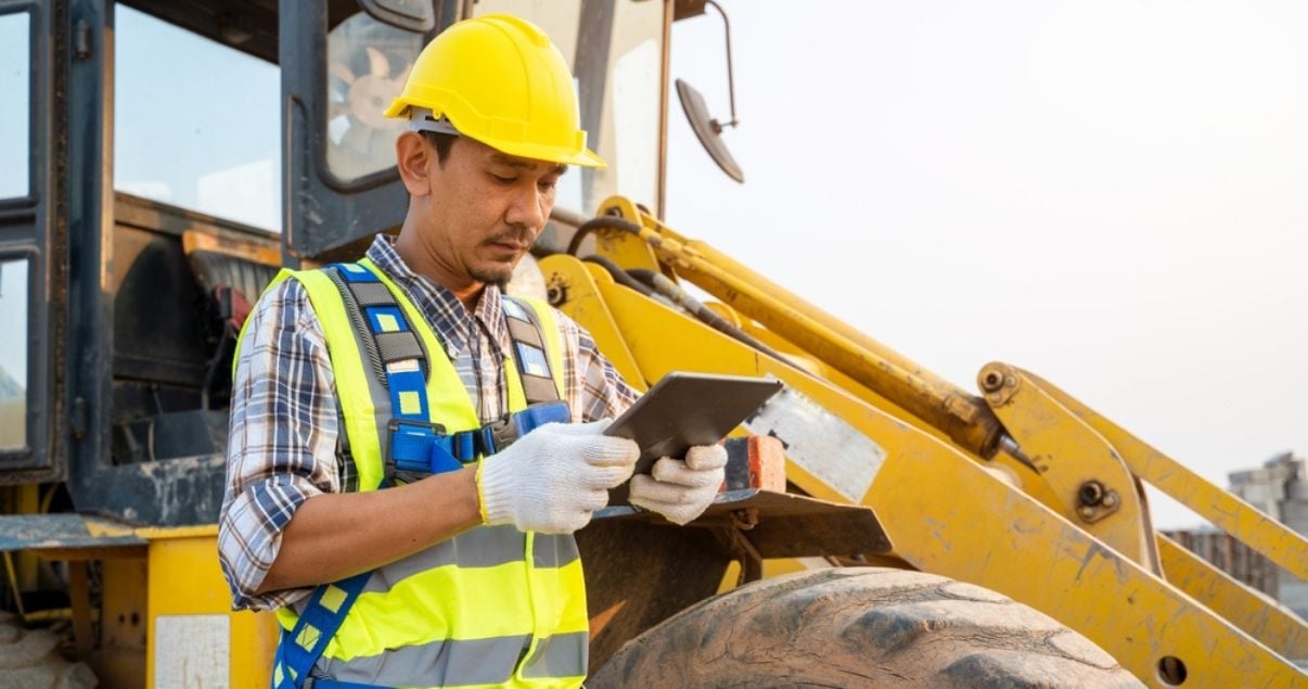 Male construction worker filling out a mobile form on a tablet