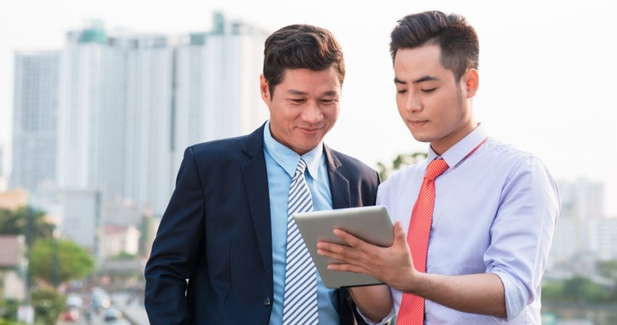 Businessmen looking a mobile form on a tabled having swithced away from paper forms