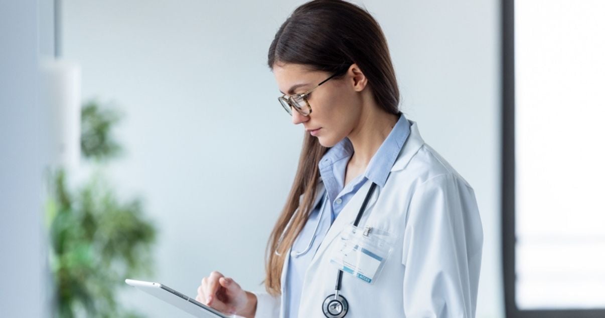 Female brunette doctor downloading a mobile forms app on her mobile device