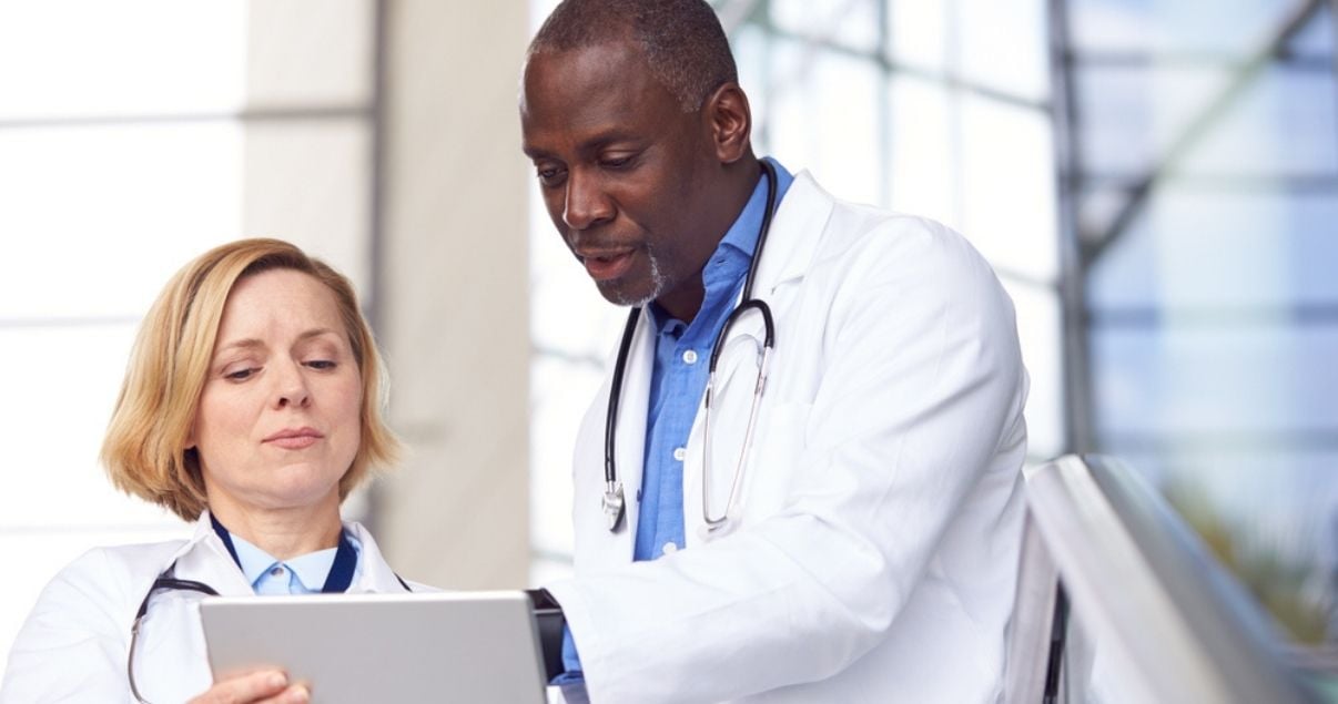 Female and male doctor partners viewing data collected through mobile forms on a tablet