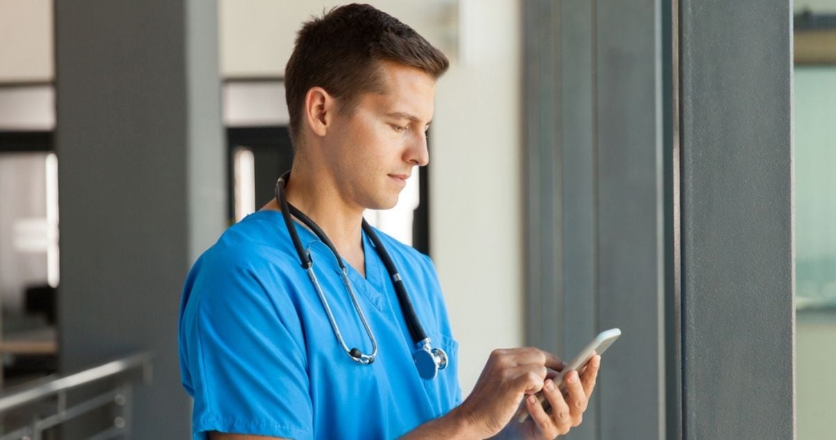 Young brunette doctor filling out a mobile form on his phone using Kizeo Forms