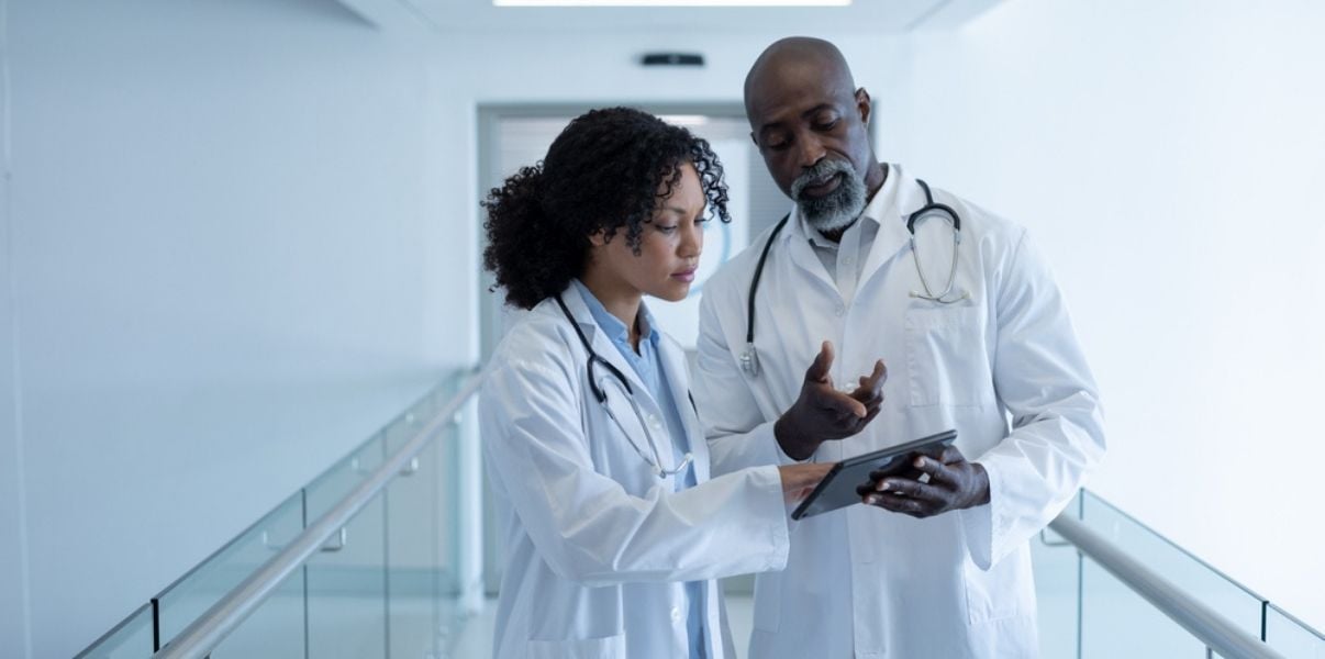 Male and female colleague doctors discussing organisational insights at a hospital corridor