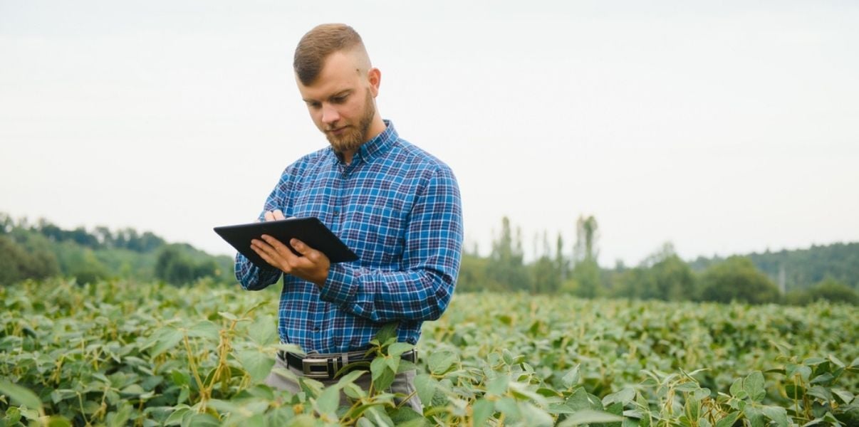 Young male engineer collecting data with mobile forms to ease farm management